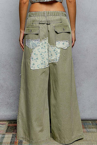 Green patchwork pants worn by a person against a plain background