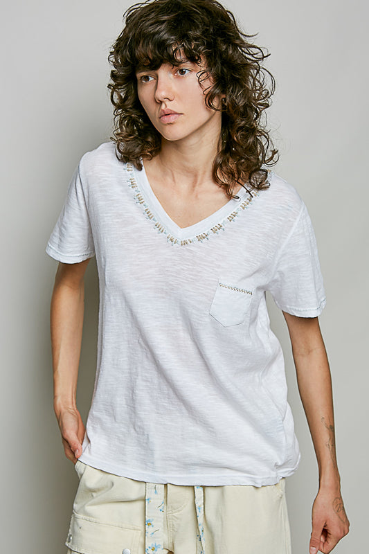 Person wearing a white t-shirt with a subtle pattern on a plain background