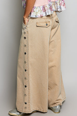 Person wearing a long beige skirt with button details on a plain background