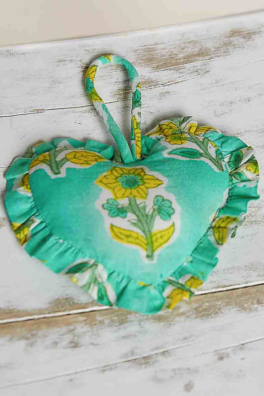 Heart-shaped fabric bag charm with floral design on a wooden surface