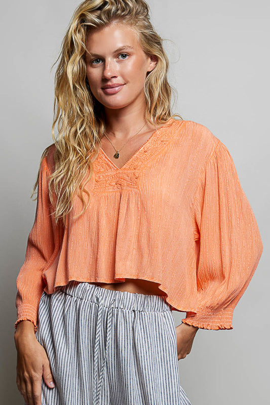 Woman wearing an orange blouse with a gray background
