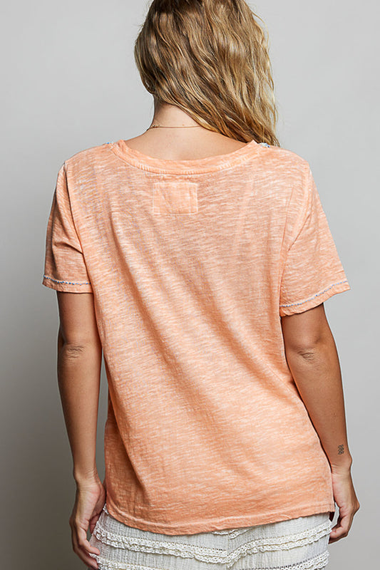 Person wearing a peach-colored t-shirt against a plain background