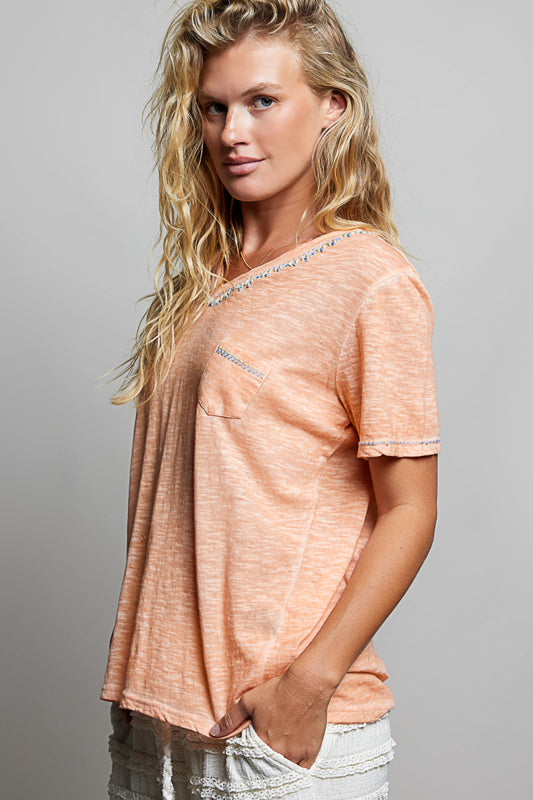 Woman wearing a peach-colored t-shirt against a gray background