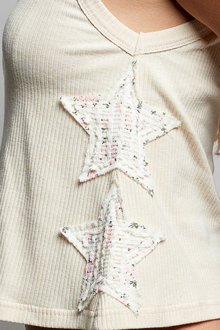 Beige top with star-shaped floral patches on a plain background