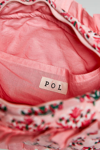 Close-up of a pink fabric with a 'POL' label, featuring floral patterns.