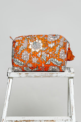 an orange cosmetic case on a stool against a neutral background. 