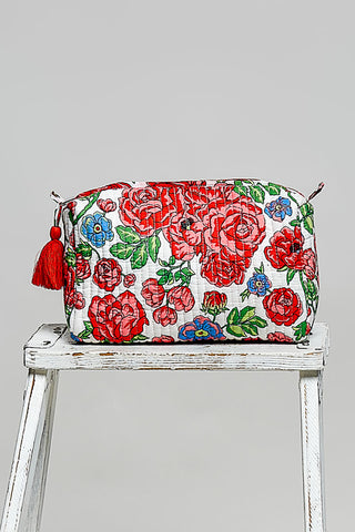 Floral-patterned pouch with tassels on a white stool against a gray background
