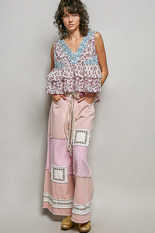 A women wearing a pink and blue floral top against a neutral background.