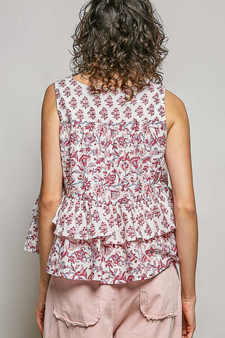 A women wearing a pink and blue floral top against a neutral background.