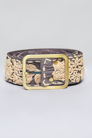 A rolled-up belt featuring a dark brown base with intricate beige floral embroidery and a prominent gold-tone metal buckle.