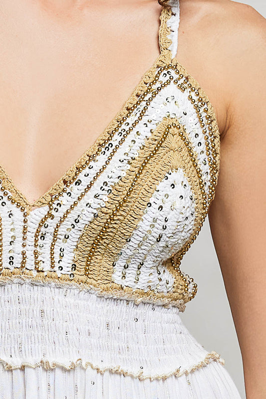 Close-up of a white and gold beaded top with a plain background