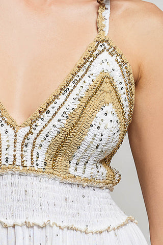 Close-up of a white and gold beaded top with a plain background