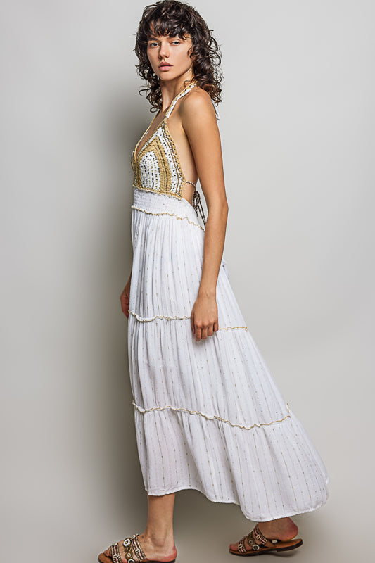 Woman wearing a white and gold dress against a plain background
