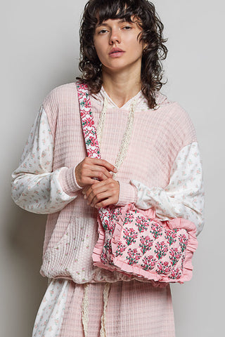 Woman holding a pink floral bag against a plain background