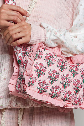 Close-up of a pink floral dress with ruffles and a person's hands adjusting it.