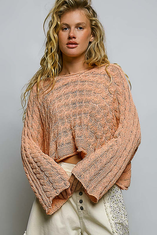 Woman wearing a pink knitted sweater against a gray background