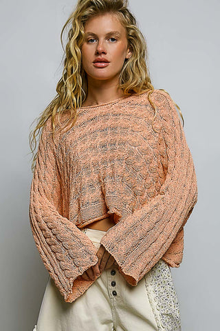 Woman wearing a pink knitted sweater against a gray background