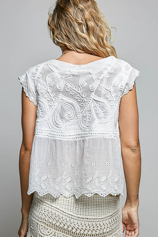 White lace top worn by a person on a gray background