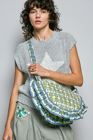 Woman holding a floral-patterned bag against a plain background