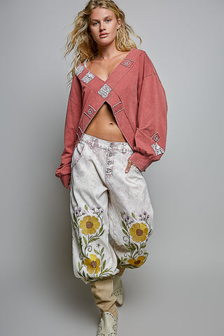 Person wearing a pink jacket and floral pants on a gray background