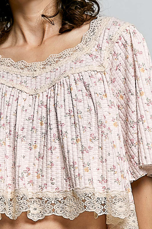 Close up of a Floral blouse with lace details on a plain background