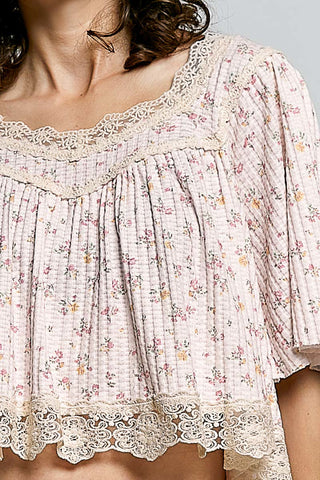 Close up of a Floral blouse with lace details on a plain background