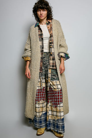 A women wearing a beige cardigan and printed pants against a neutral background.