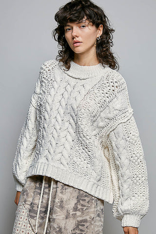 Woman wearing a textured white sweater against a gray background