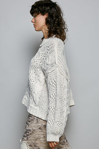 Woman wearing a white textured sweater against a gray background