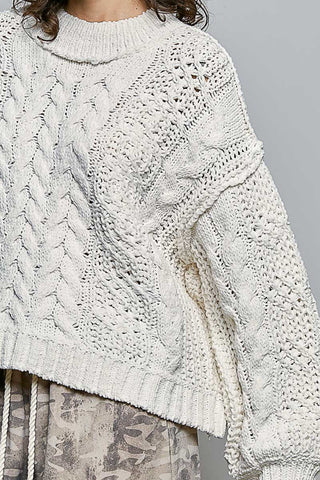 Close-up of a person wearing a textured white sweater against a neutral background