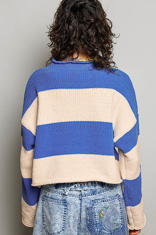A person viewed from the back wearing a cropped knit sweater with wide horizontal stripes in royal blue and cream, paired with light blue denim jeans against a plain light gray background.