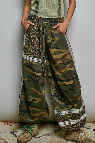 Person wearing camouflage and leopard print pants with a plain background