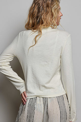 A women wearing a mock neck turtleneck against a neutral background.