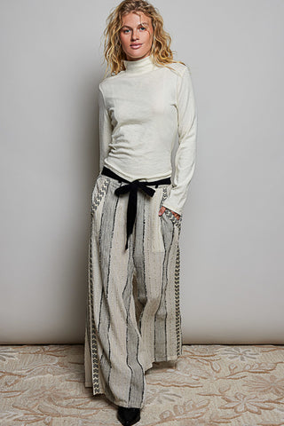 A women wearing a mock neck turtleneck against a neutral background.