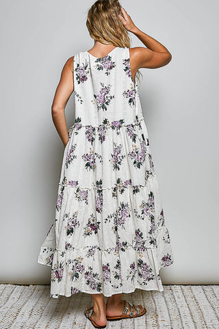 A women wearing a floral maxi dress against a neutral background.