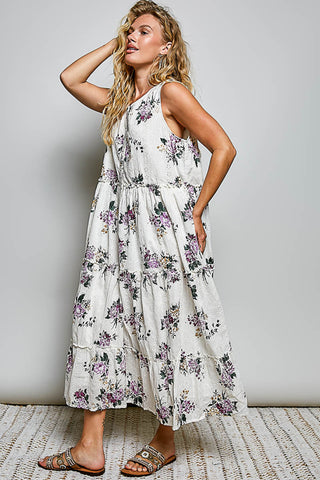 A women wearing a floral maxi dress against a neutral background.