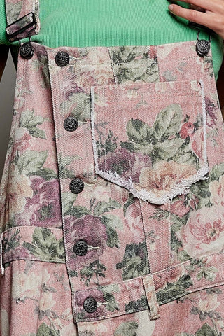 Floral patterned denim overalls with a green shirt underneath