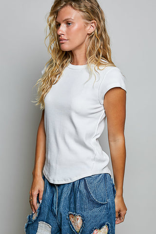 A woman wearing a plain white short-sleeve crewneck t-shirt and distressed blue denim shorts, photographed against a neutral gray studio background.