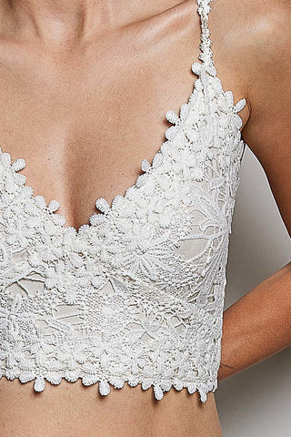White lace camisole top with floral embroidery and scalloped edges, shown on a model.