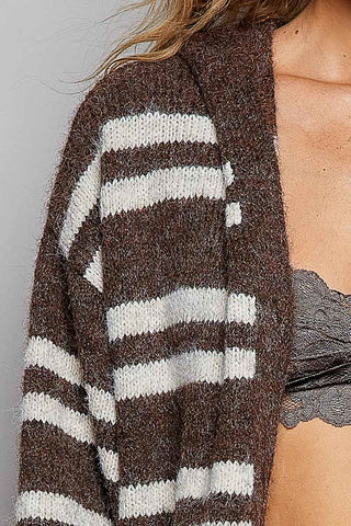 A close-up of a person wearing a fuzzy knit open-front cardigan with wide brown and off-white horizontal stripes. The cardigan is shown on a model against a plain light gray background.