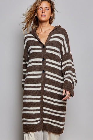 A woman modeling a brown and cream striped knit cardigan with a hood and front buttons, photographed against a plain light gray studio background.