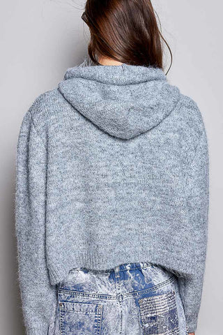 A person shown from the back wearing a light heather gray cropped knit hoodie and distressed blue jeans against a plain light gray background.