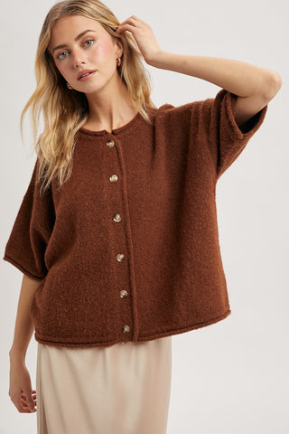 Woman wearing a brown cardigan with a plain background