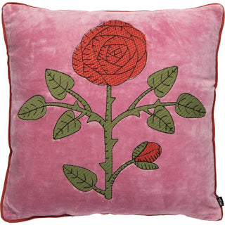 A square pink velvet throw pillow featuring a large embroidered red rose with green leaves on the front.