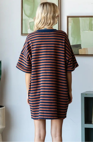 Person wearing a striped dress in a room with framed pictures on the wall.