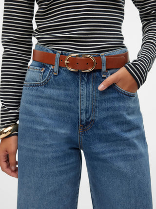 Person wearing blue jeans with a brown belt and striped shirt on a white background