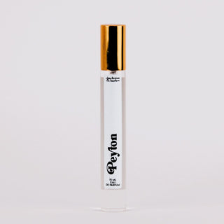 Perfume bottle with gold cap and white label on a light gray background