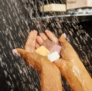 Close-up of hands holding colorful soap bars under running water