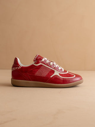 Red sneaker with white accents on a beige background