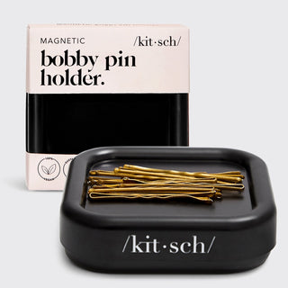Black magnetic bobby pin holder with gold pins and 'kitsch' packaging on a light gray background